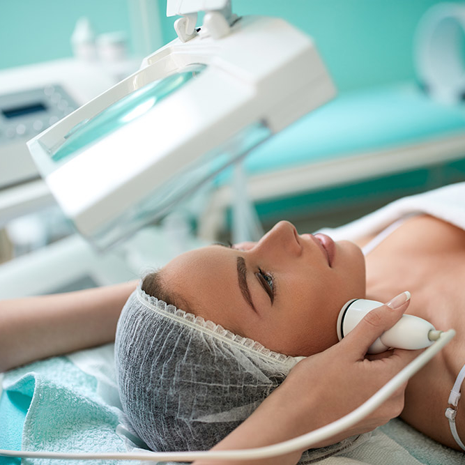 Close up of cosmetologist  hands doing 4D laser lifting face and body treatment on female  face